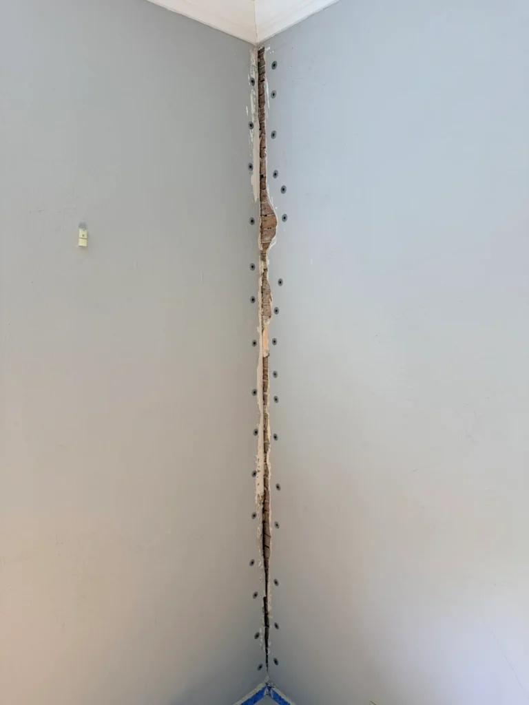 Removing loose and crumbling lath and plaster from an old wall to prepare for repair.