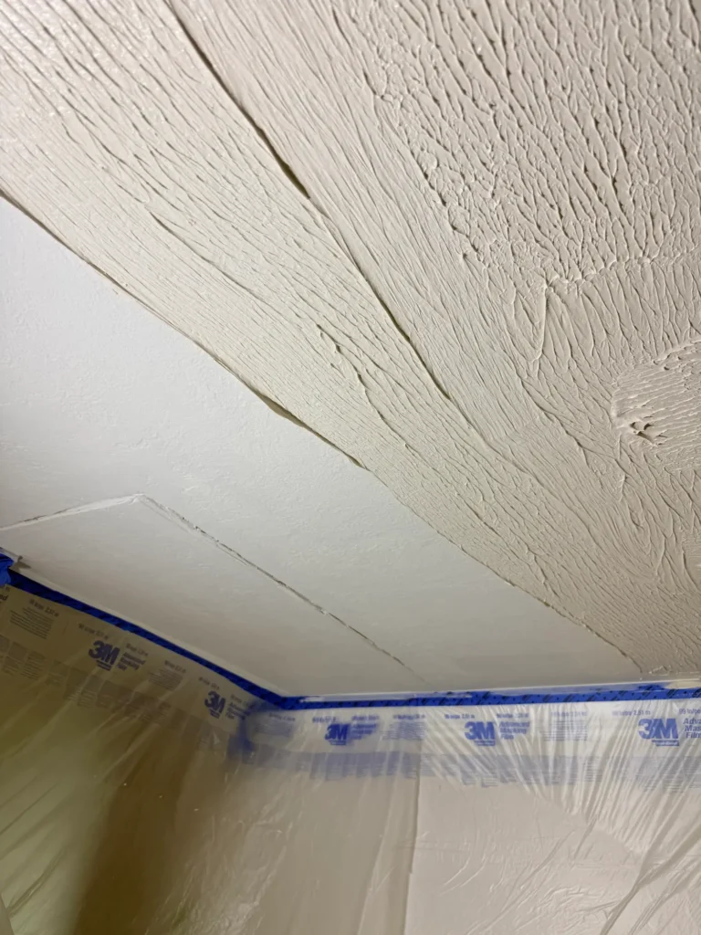 Applying joint compound to float the ceiling and level the surface during the smoothing process.