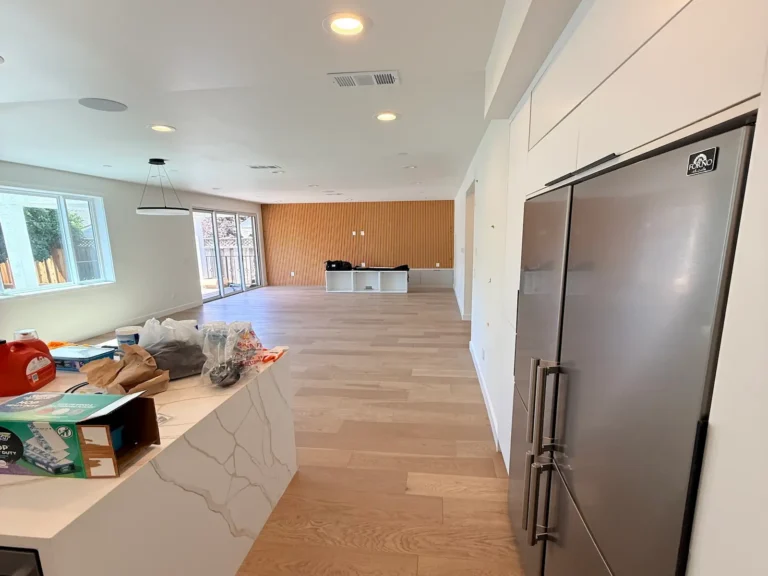 Finished interior painting in an open-plan living room: smooth white walls and ceiling next to a wood slat accent wall