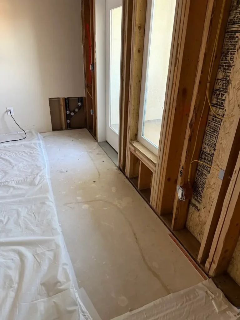 Water damage drywall repair in a San Jose home: wet drywall removed down to the studs around the windows after mitigation, ready for rebuild