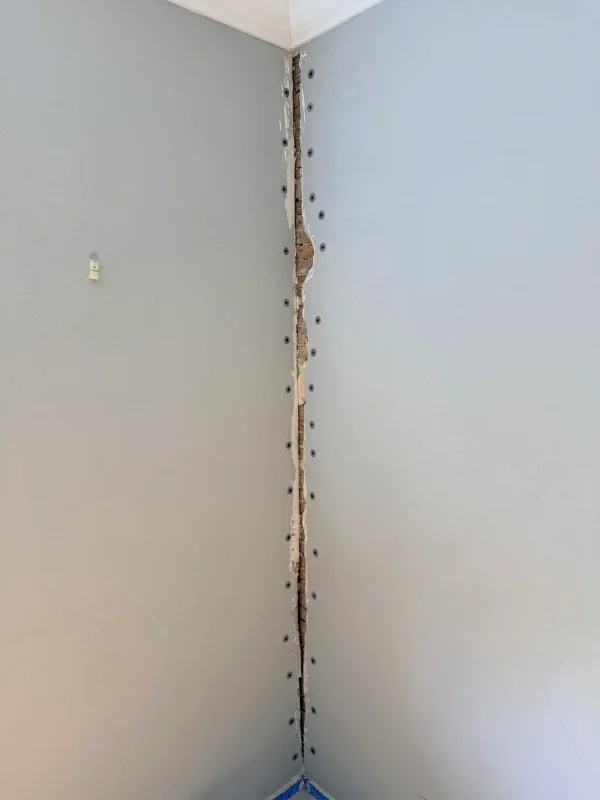 Removing loose and crumbling lath and plaster from an old wall to prepare for repair.